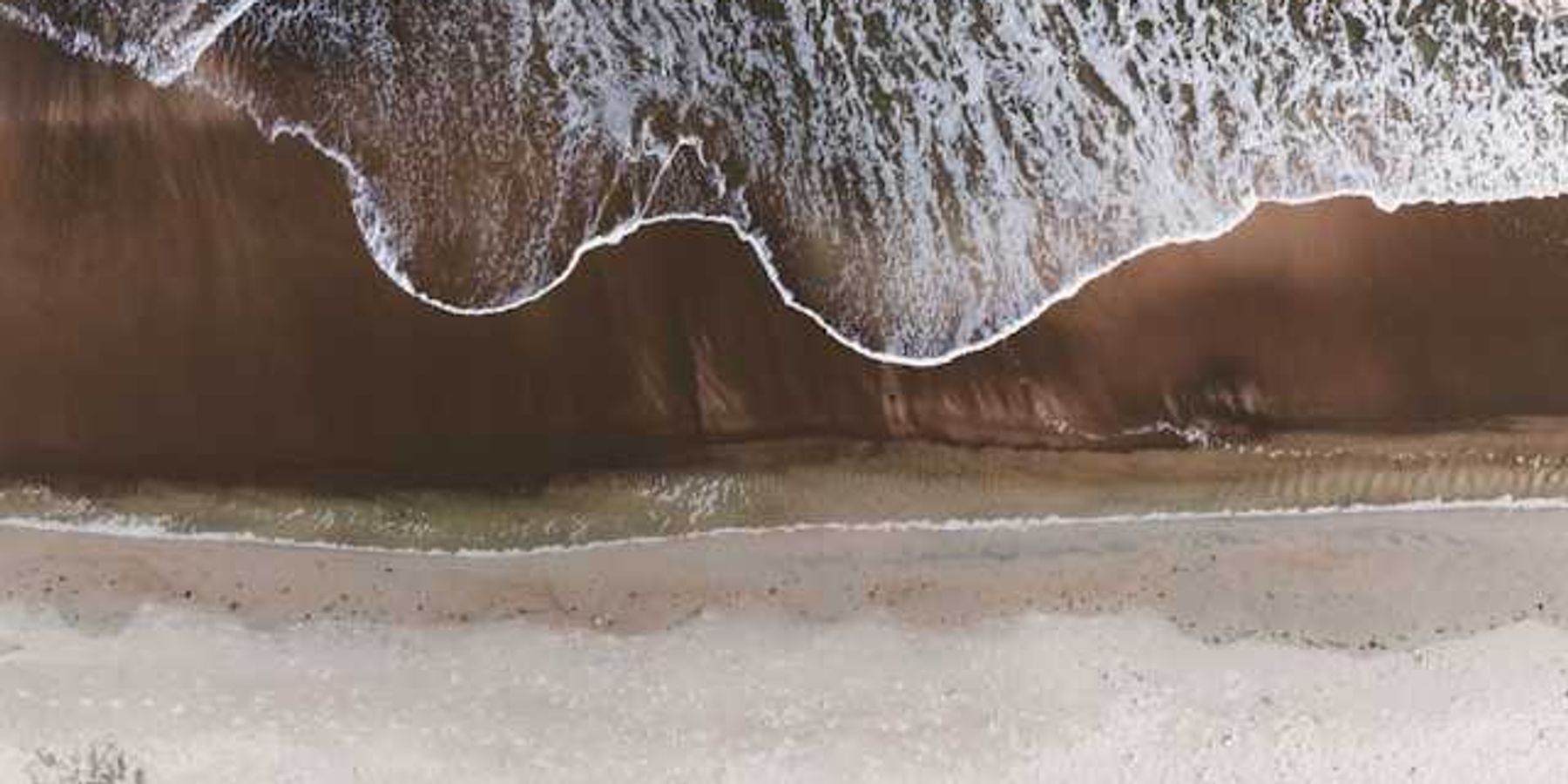 An aerial view of a beach with the waves encroaching