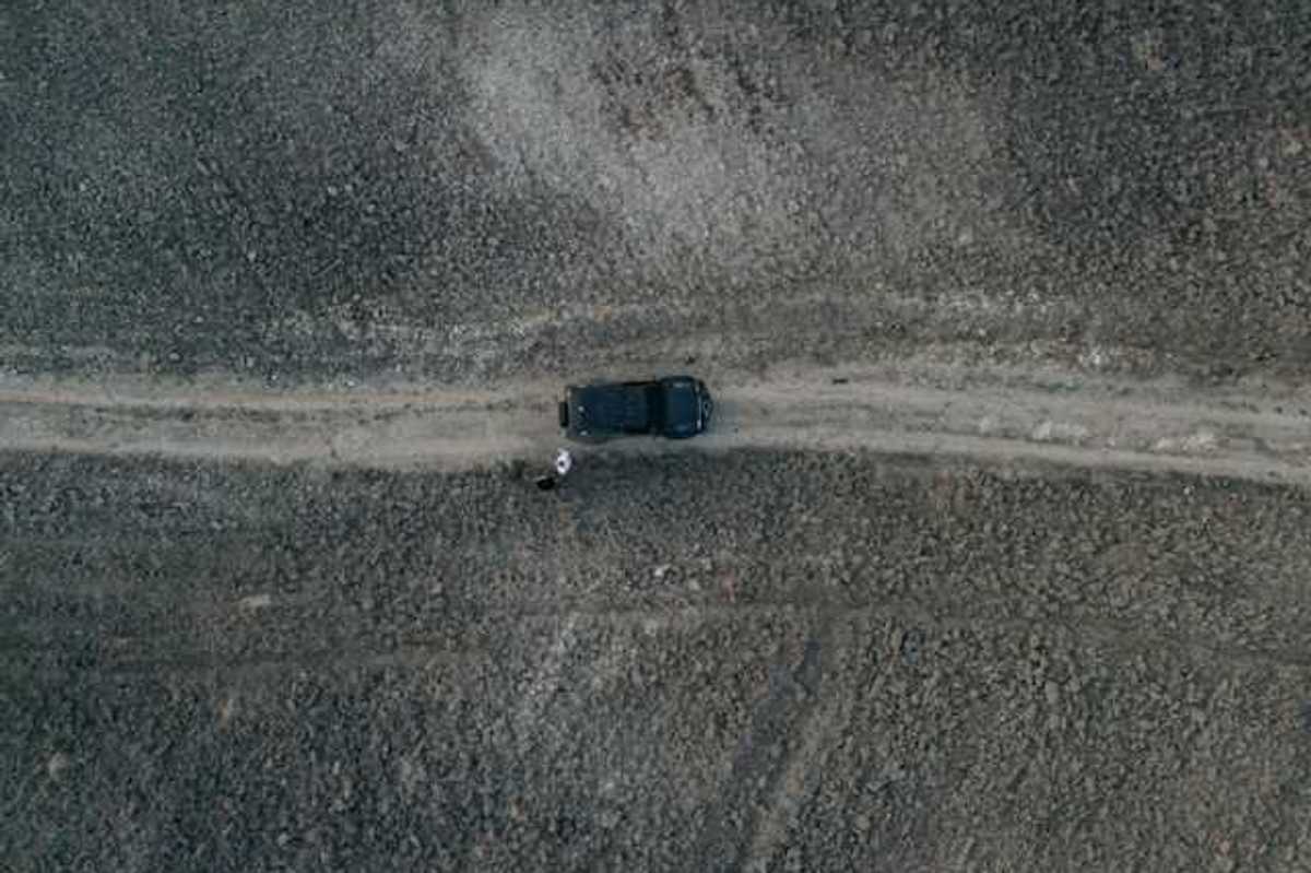 An aerial view of a car on a lonely dirt road