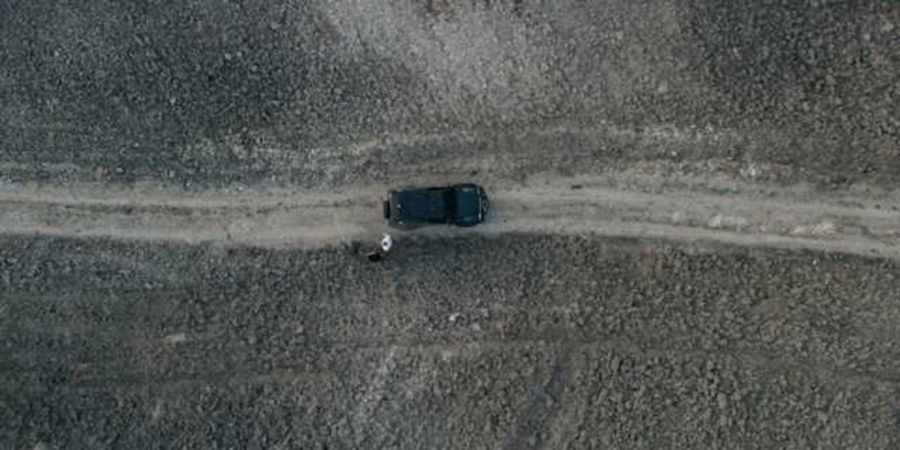 An aerial view of a car on a lonely dirt road