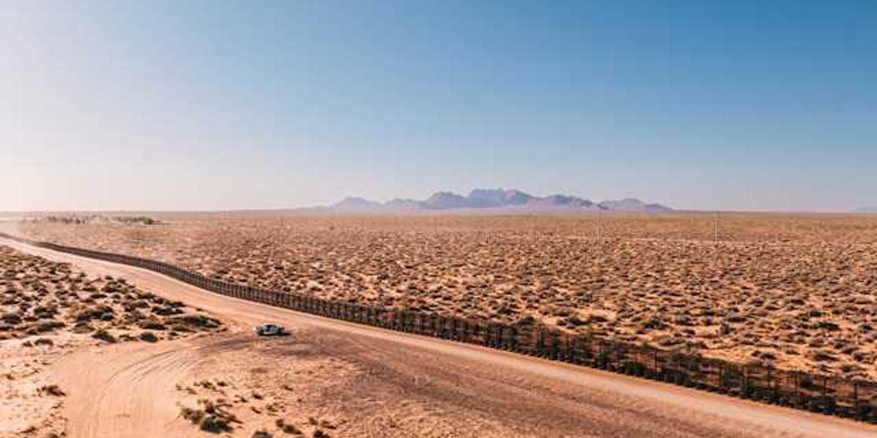 An aerial view of a dry, desert location with mountains the background