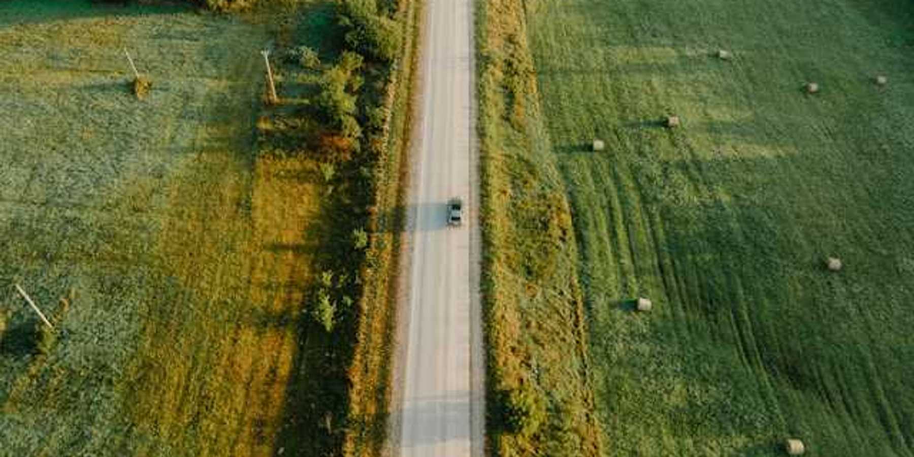 An aerial view of a highway between green fields