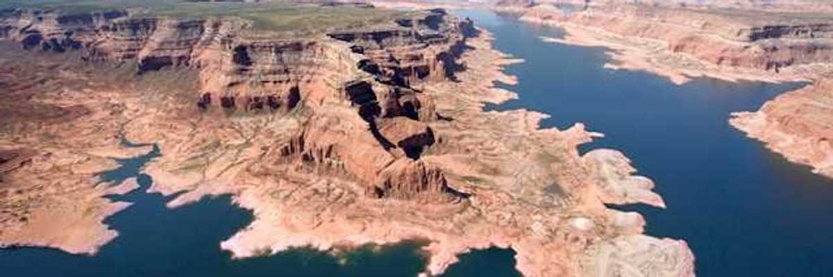 An aerial view of a lake stretching between dry bluffs in a desert landscape