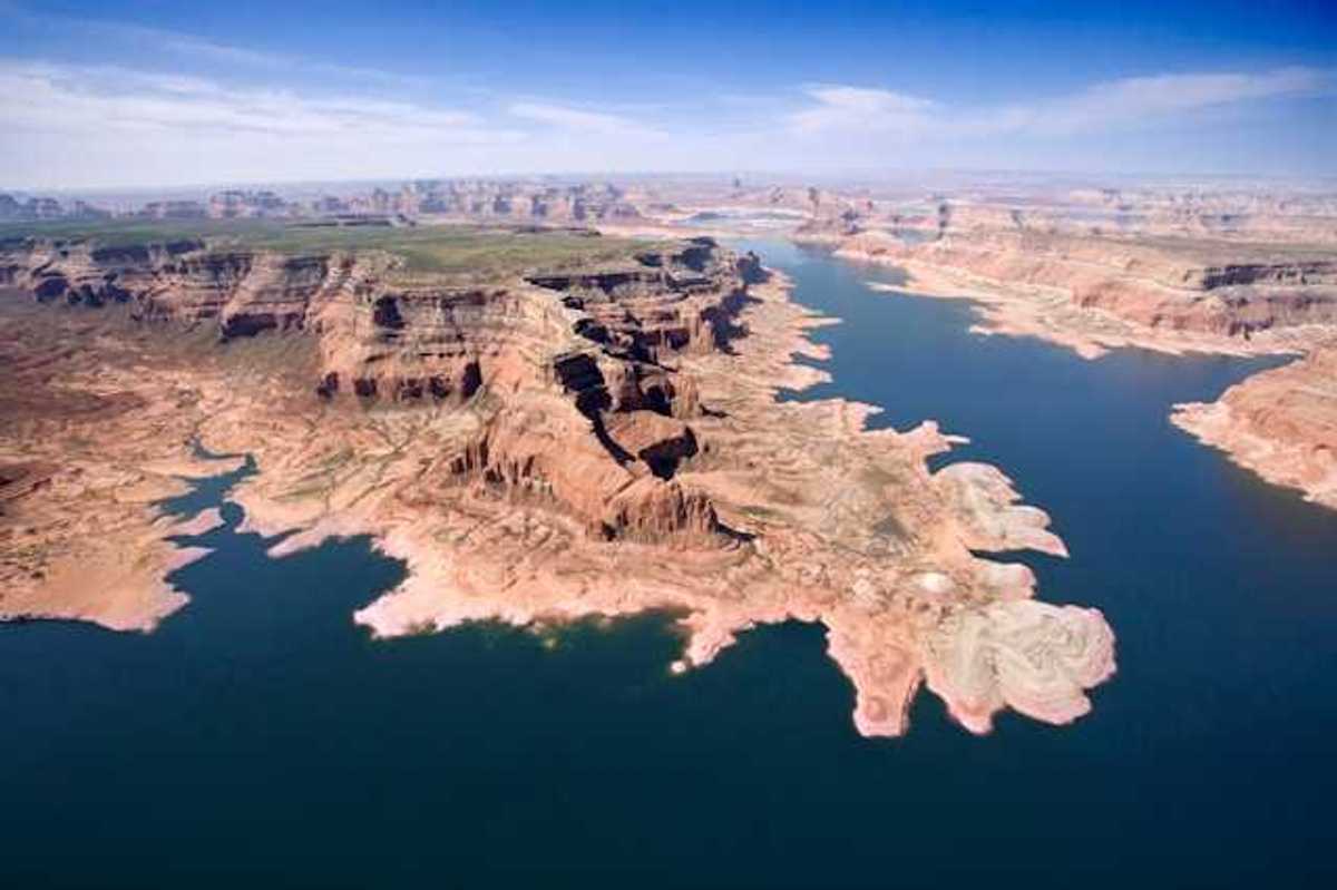 An aerial view of a lake stretching between dry bluffs in a desert landscape