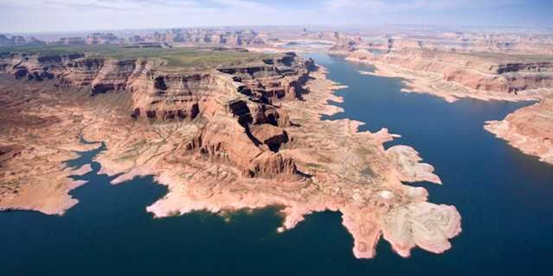An aerial view of a lake stretching between dry bluffs in a desert landscape