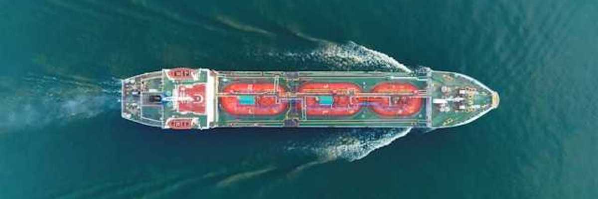 An aerial view of a large ship moving through green ocean water
