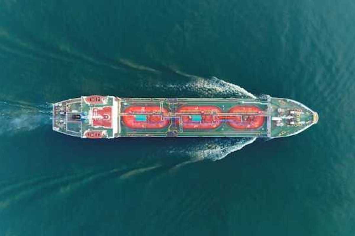 An aerial view of a large ship moving through green ocean water