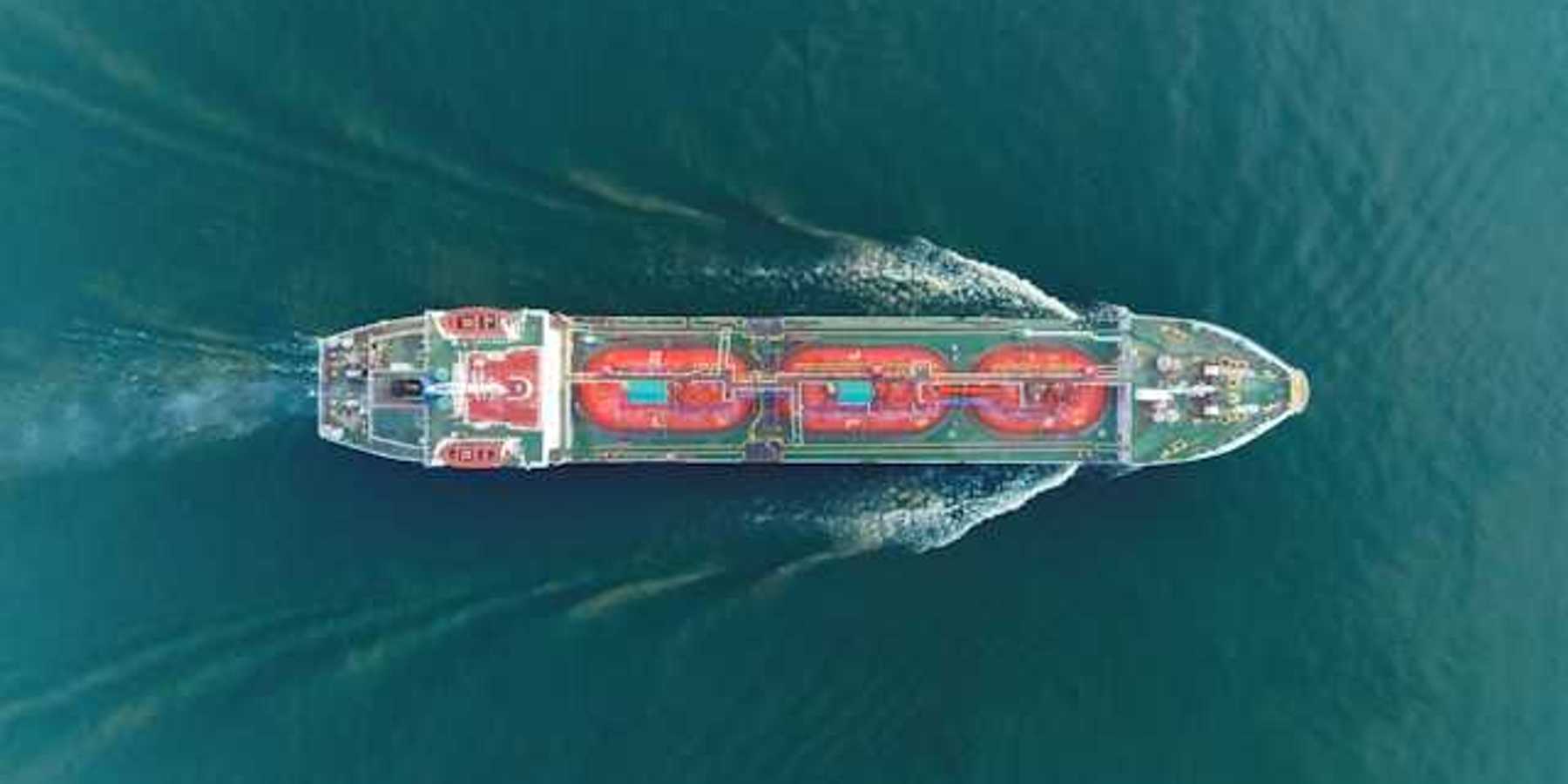 An aerial view of a large ship moving through green ocean water