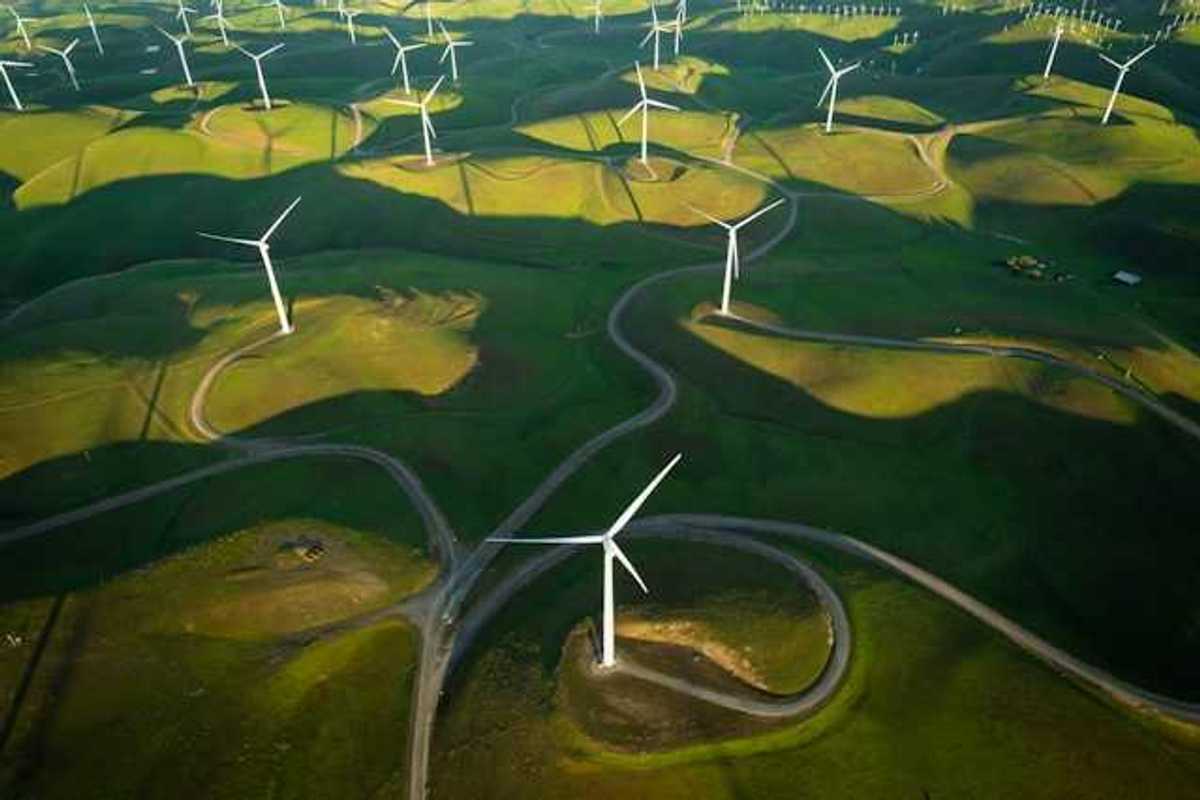 An aerial view of a log of wind turbines on a green hillside