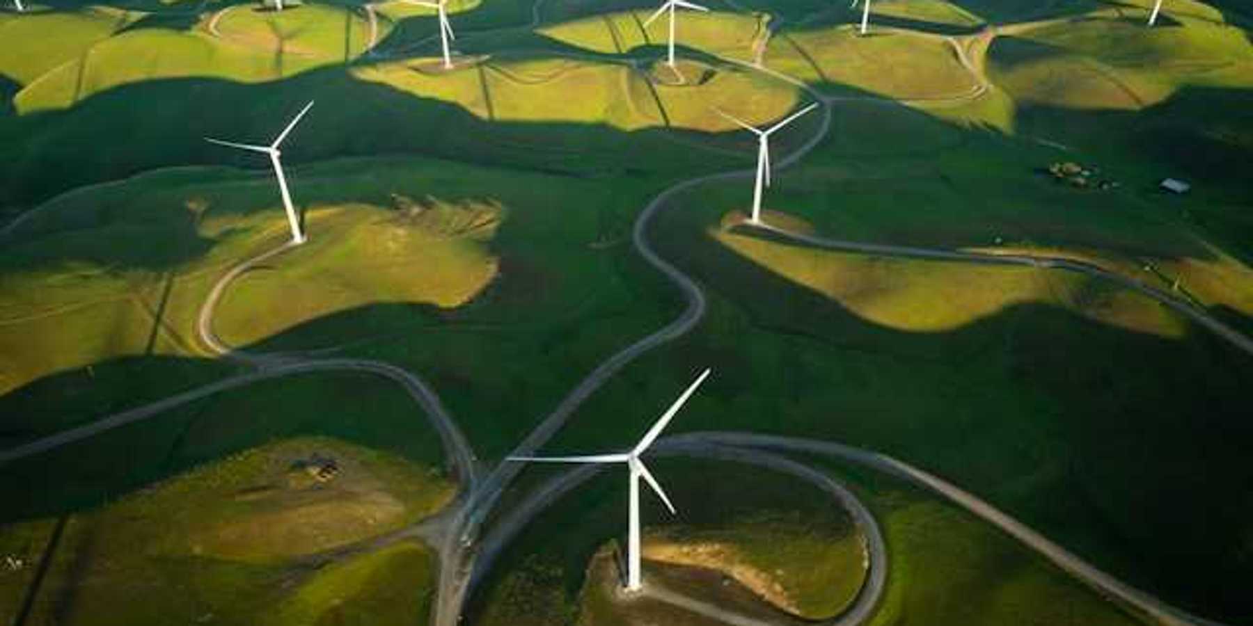 An aerial view of a log of wind turbines on a green hillside