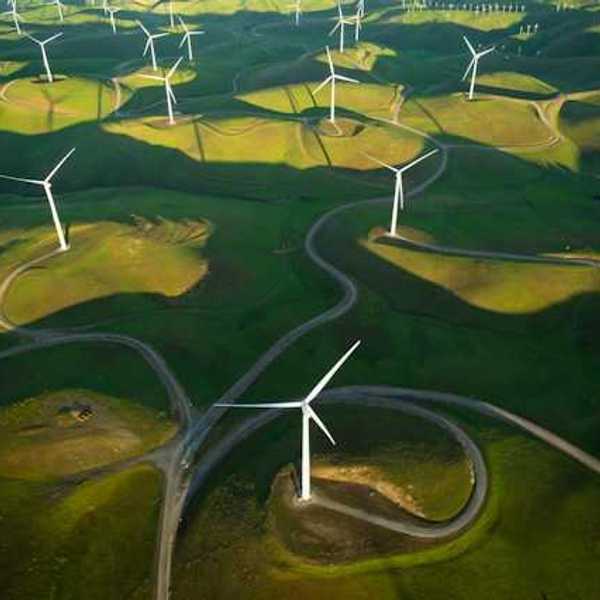 An aerial view of a log of wind turbines on a green hillside