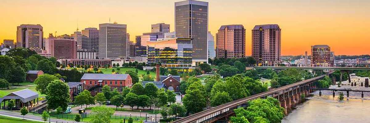 An aerial view of a railway and green trees with Richmond, VA in the background