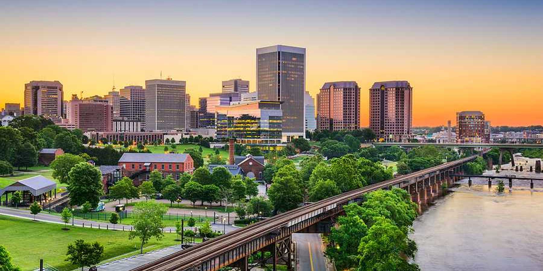 An aerial view of a railway and green trees with Richmond, VA in the background