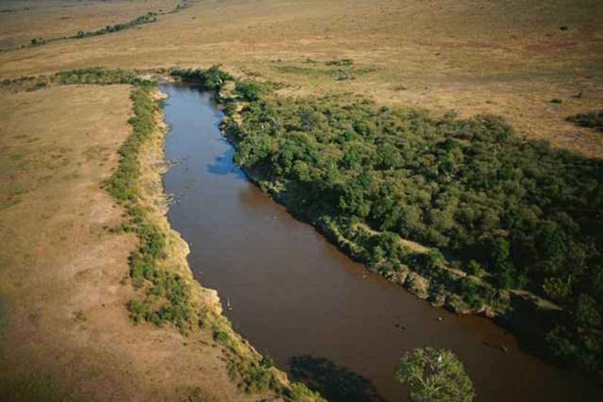 An aerial view of a river flowing between brown fields