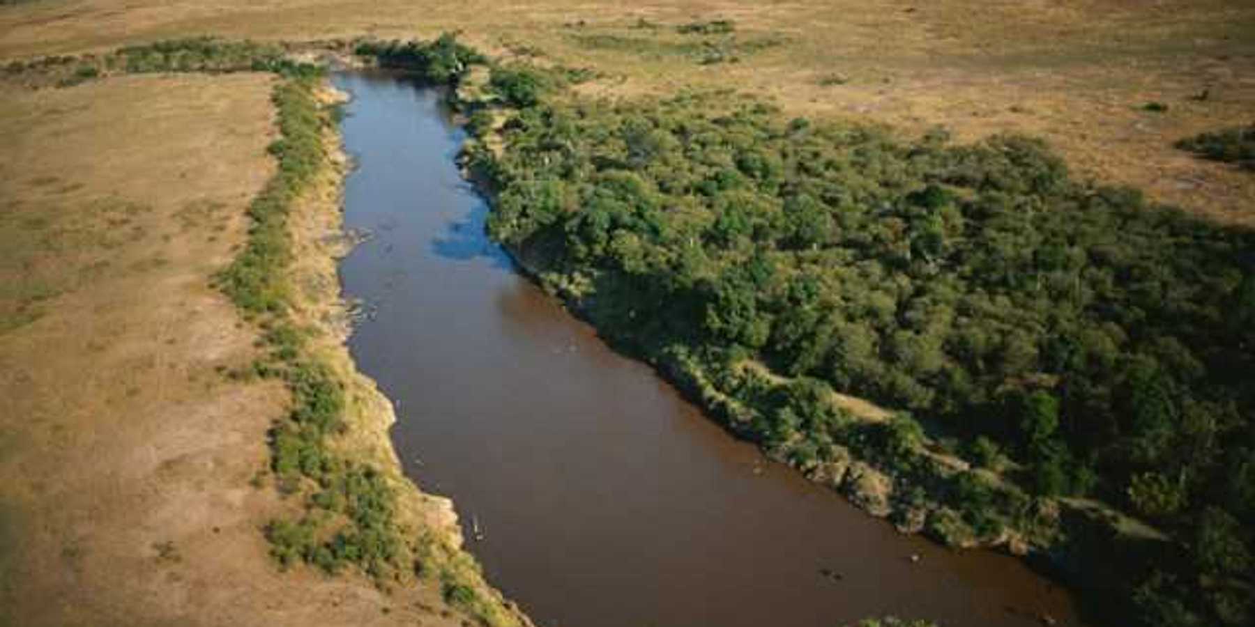 An aerial view of a river flowing between brown fields