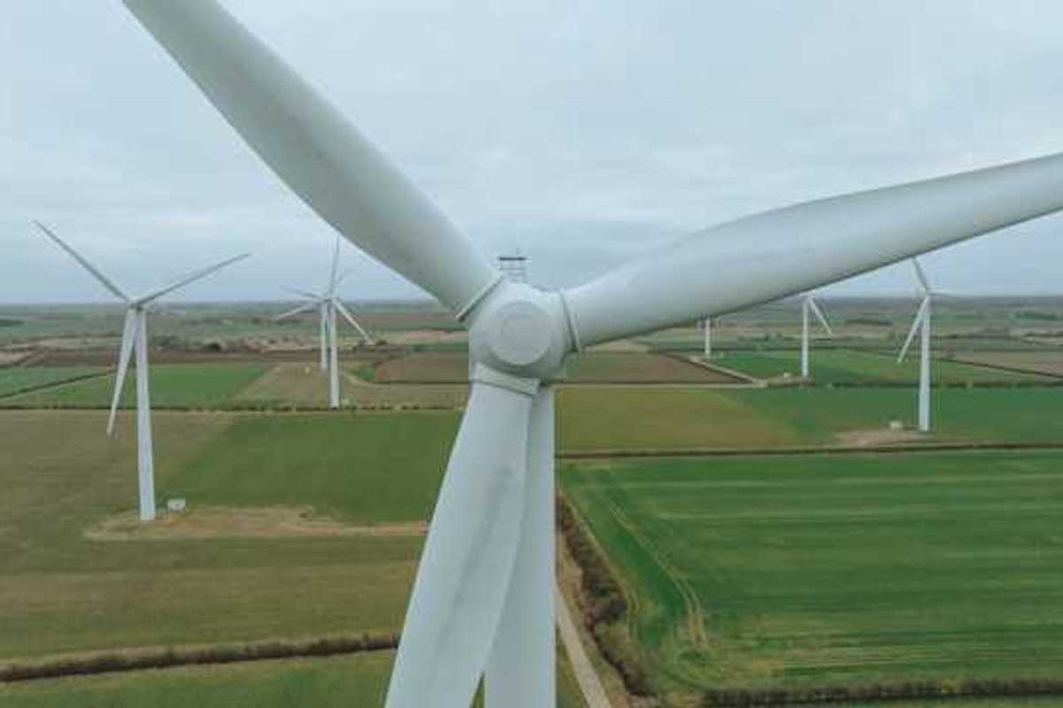 An aerial view of a row of wind turbines situated in a green field