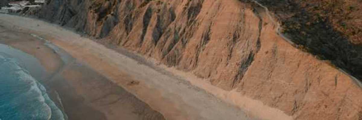 An aerial view of a sandy beach and a cliff