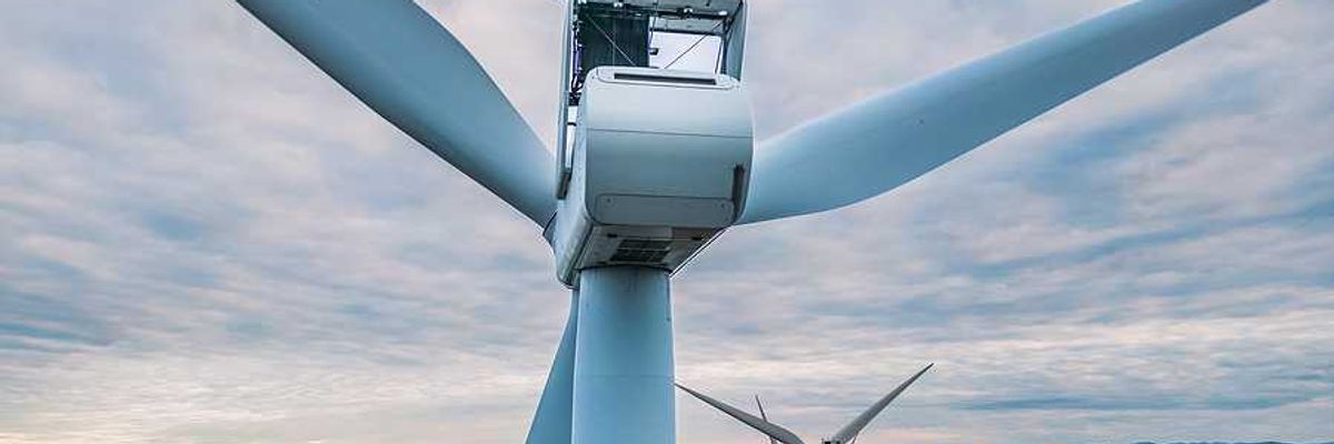 An aerial view of a set of wind turbines atop forested hills