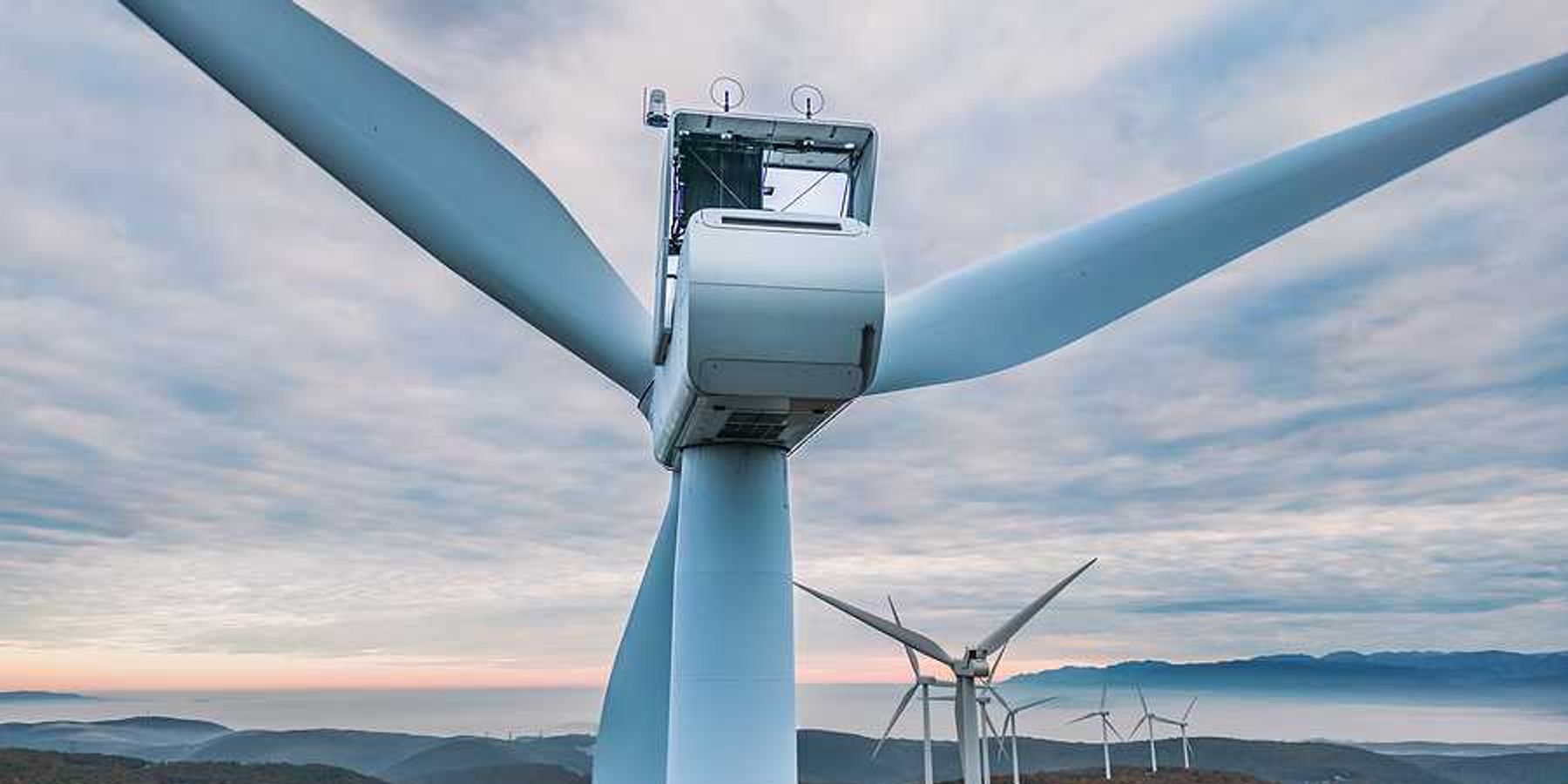 An aerial view of a set of wind turbines atop forested hills