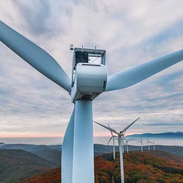 An aerial view of a set of wind turbines atop forested hills