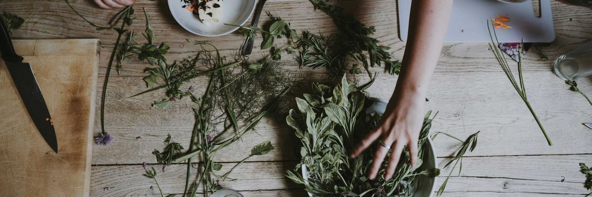 An aerial view of a wooden table with green stems being placed on plates
