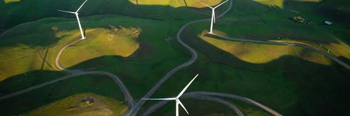 An aerial view of wind turbines sited on green hills