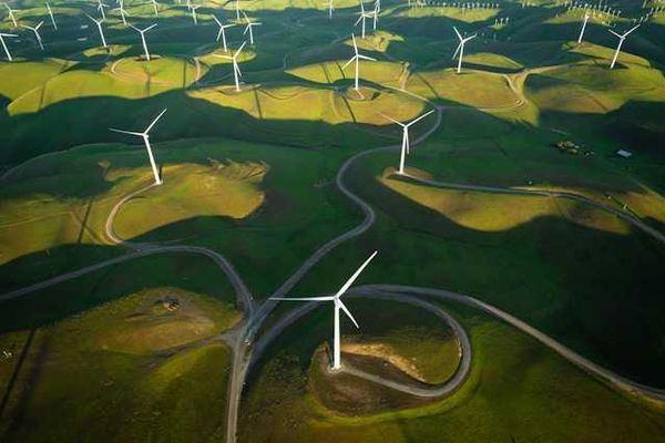 An aerial view of wind turbines sited on green hills