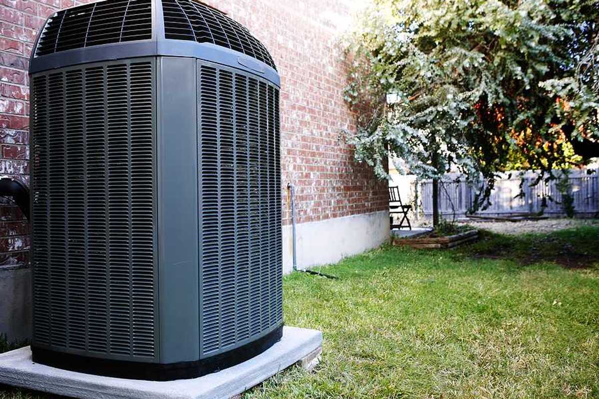An air conditioning unit sitting next to a brick house