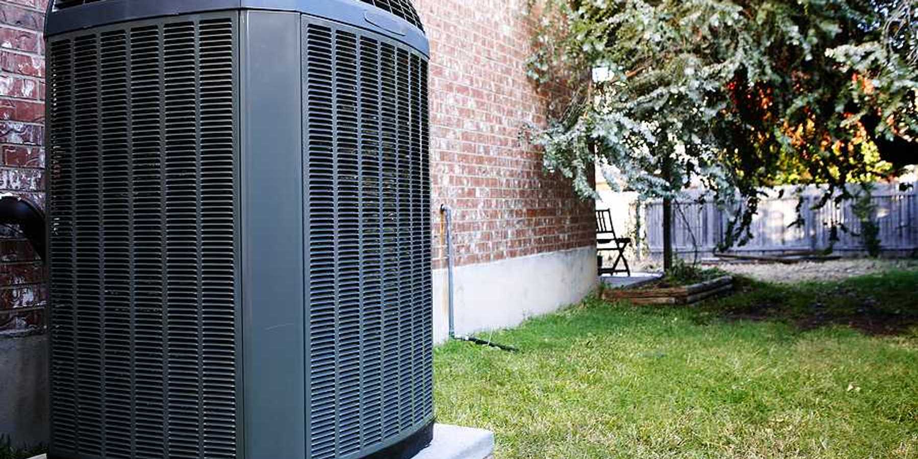 An air conditioning unit sitting next to a brick house