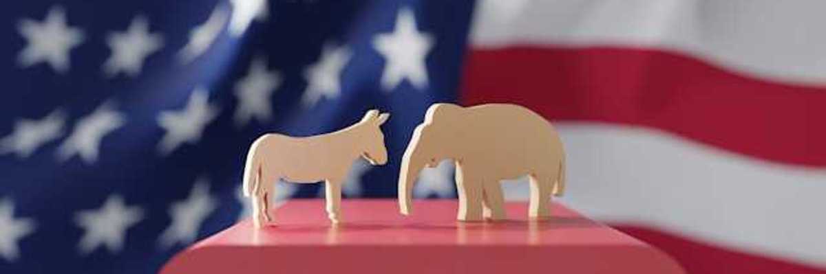 An American flag with wooden cutouts of a donkey and an elephant in the foreground