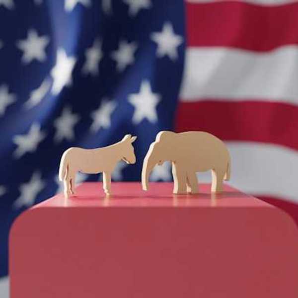 An American flag with wooden cutouts of a donkey and an elephant in the foreground