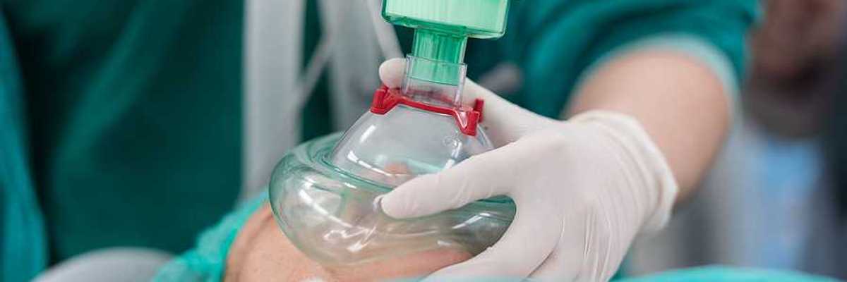 An anesthesiologist placing a cup on a patient's mouth