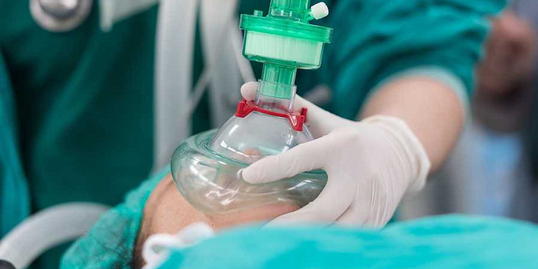 An anesthesiologist placing a cup on a patient's mouth