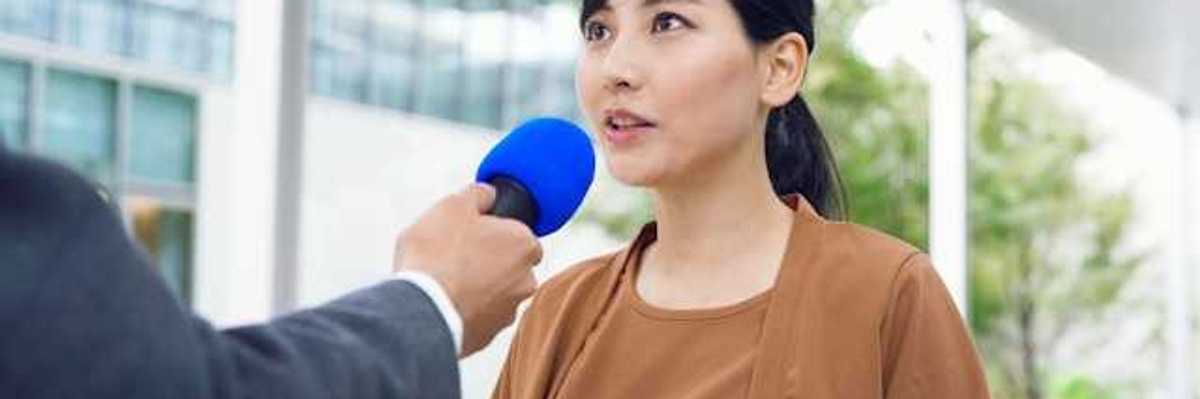 An Asian woman being interviewed by a journalist
