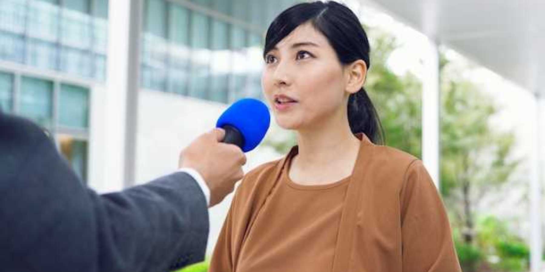 An Asian woman being interviewed by a journalist