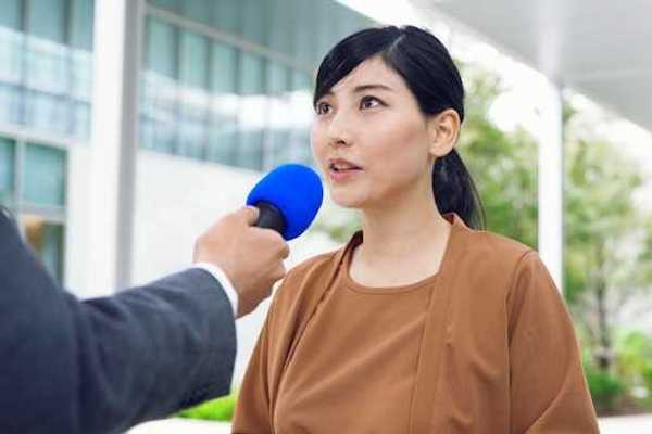 An Asian woman being interviewed by a journalist