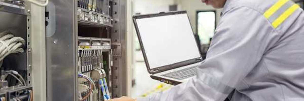 An Asian worker kneeling in front of a server with a laptop