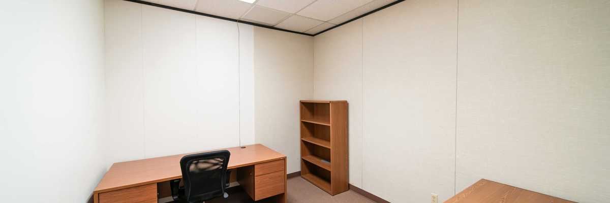 an empty office with a desk and a book shelf