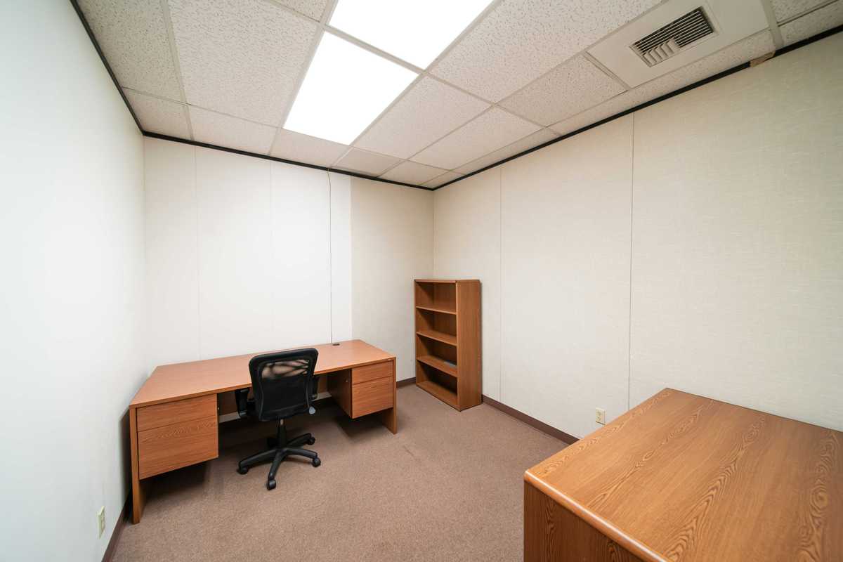 an empty office with a desk and a book shelf