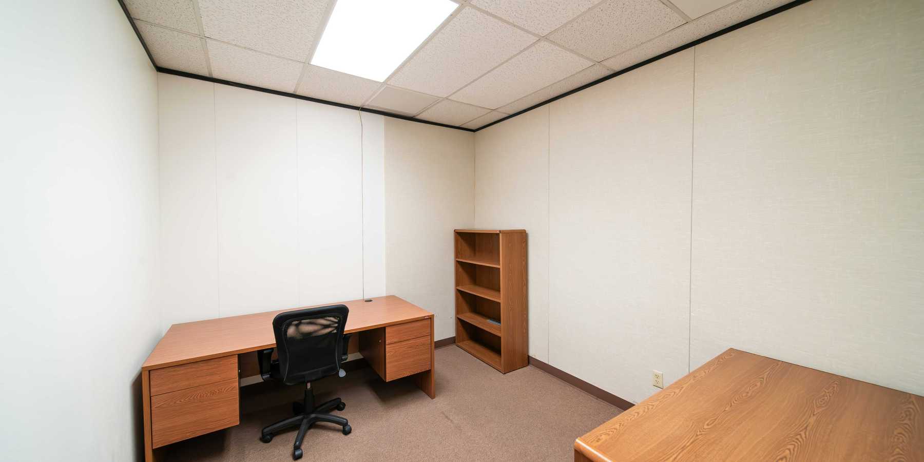 an empty office with a desk and a book shelf