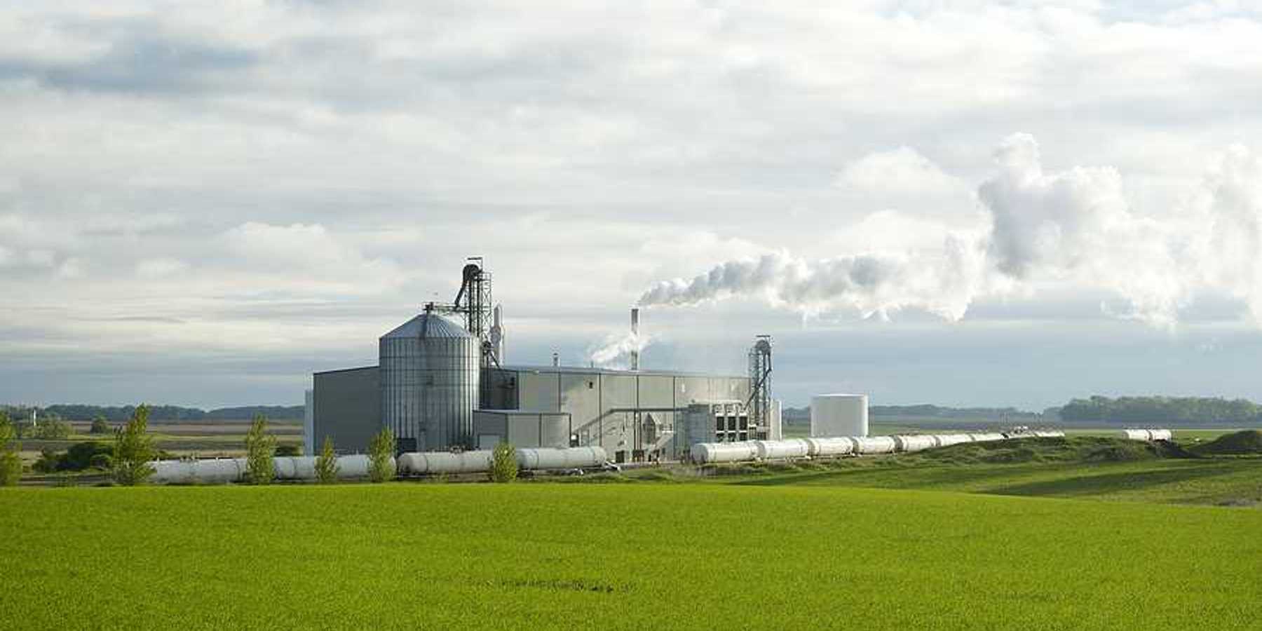 An ethanol plant with green fields in the foreground