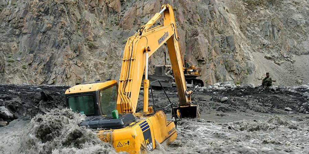 An excavator sitting on a flooded road in Pakistan