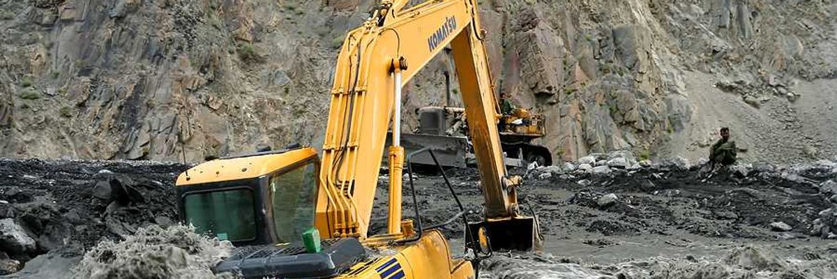 An excavator sitting on a flooded road in Pakistan