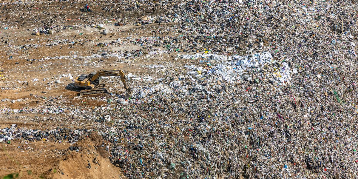 An excavator works in a massive landfill.