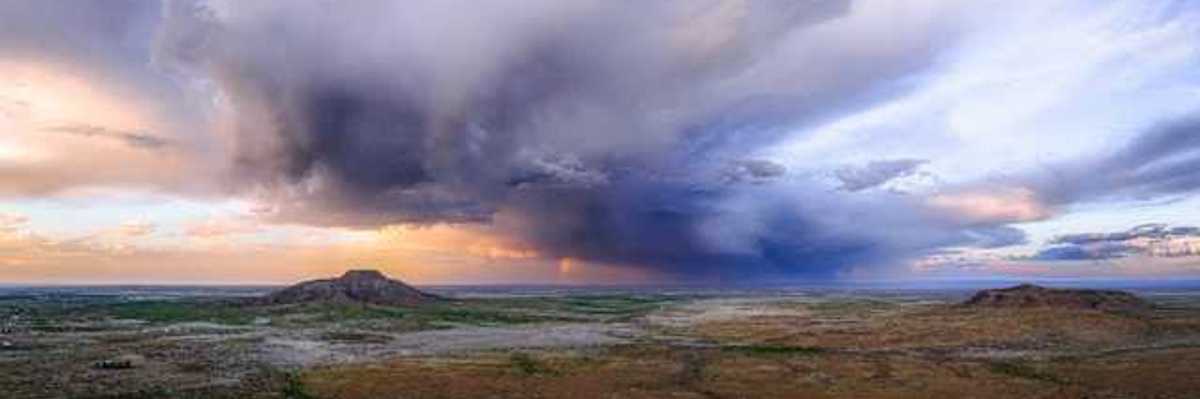 An expanse of desert with dark storm clouds building in the distance