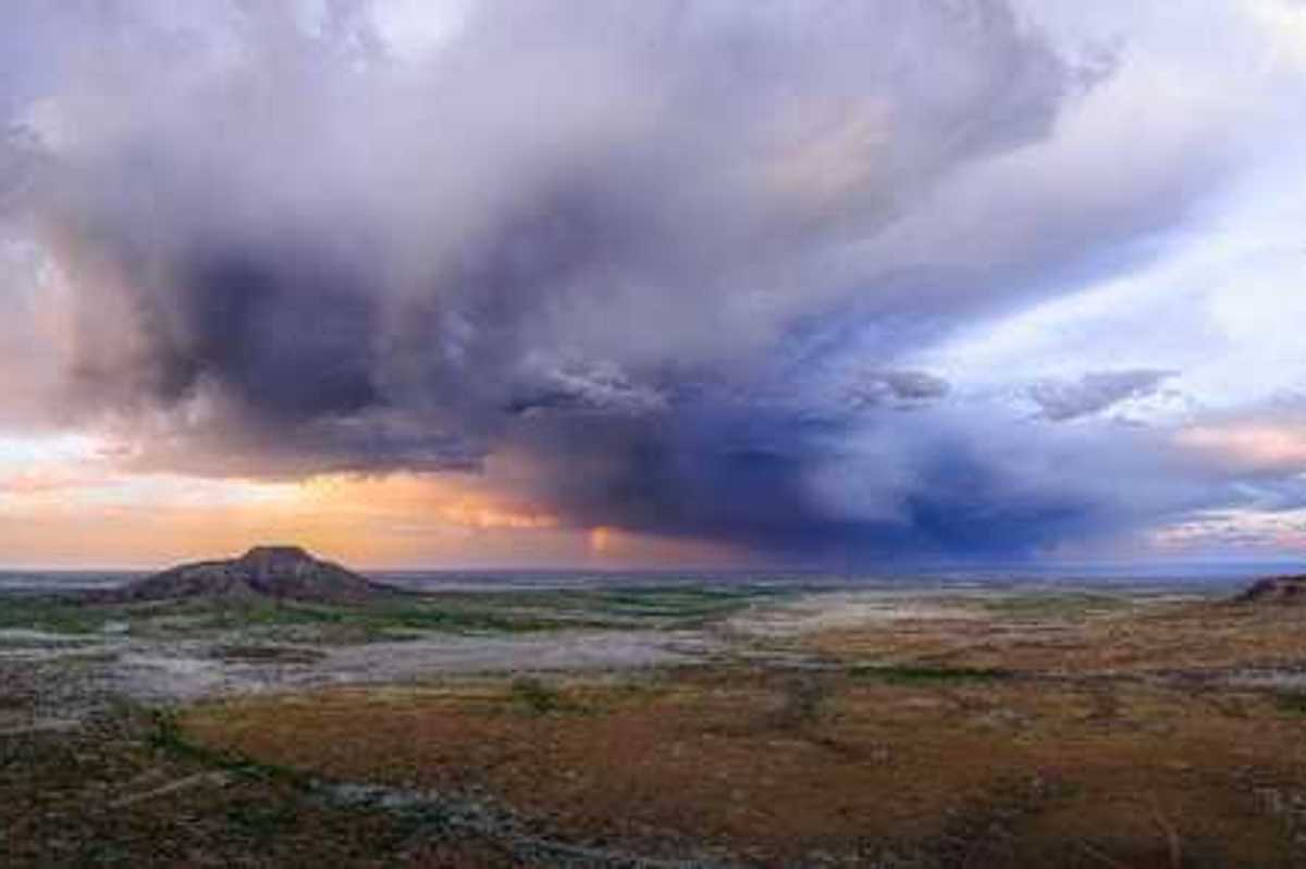 An expanse of desert with dark storm clouds building in the distance