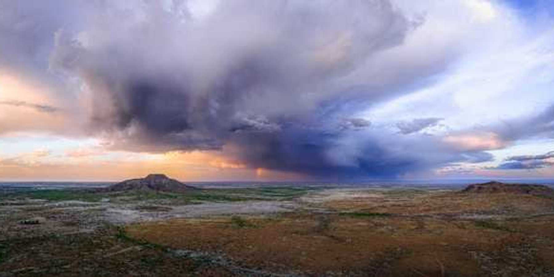 An expanse of desert with dark storm clouds building in the distance