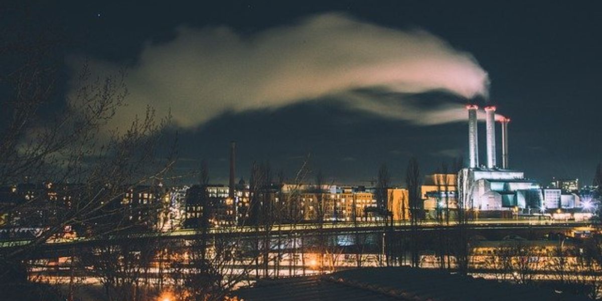 An illuminated power plant in an urban landscape at night.