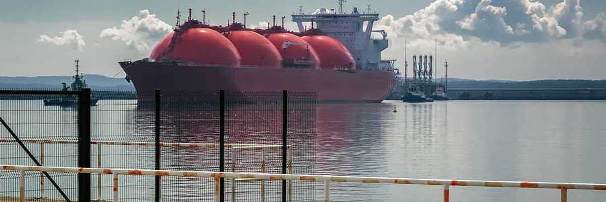 An LNG tanker ship and tugs are maneuvering for docking at a gas terminal
