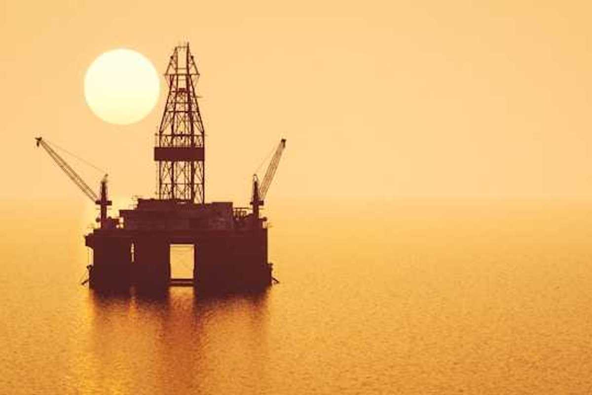 An offshore oil platform with the sun setting in the background