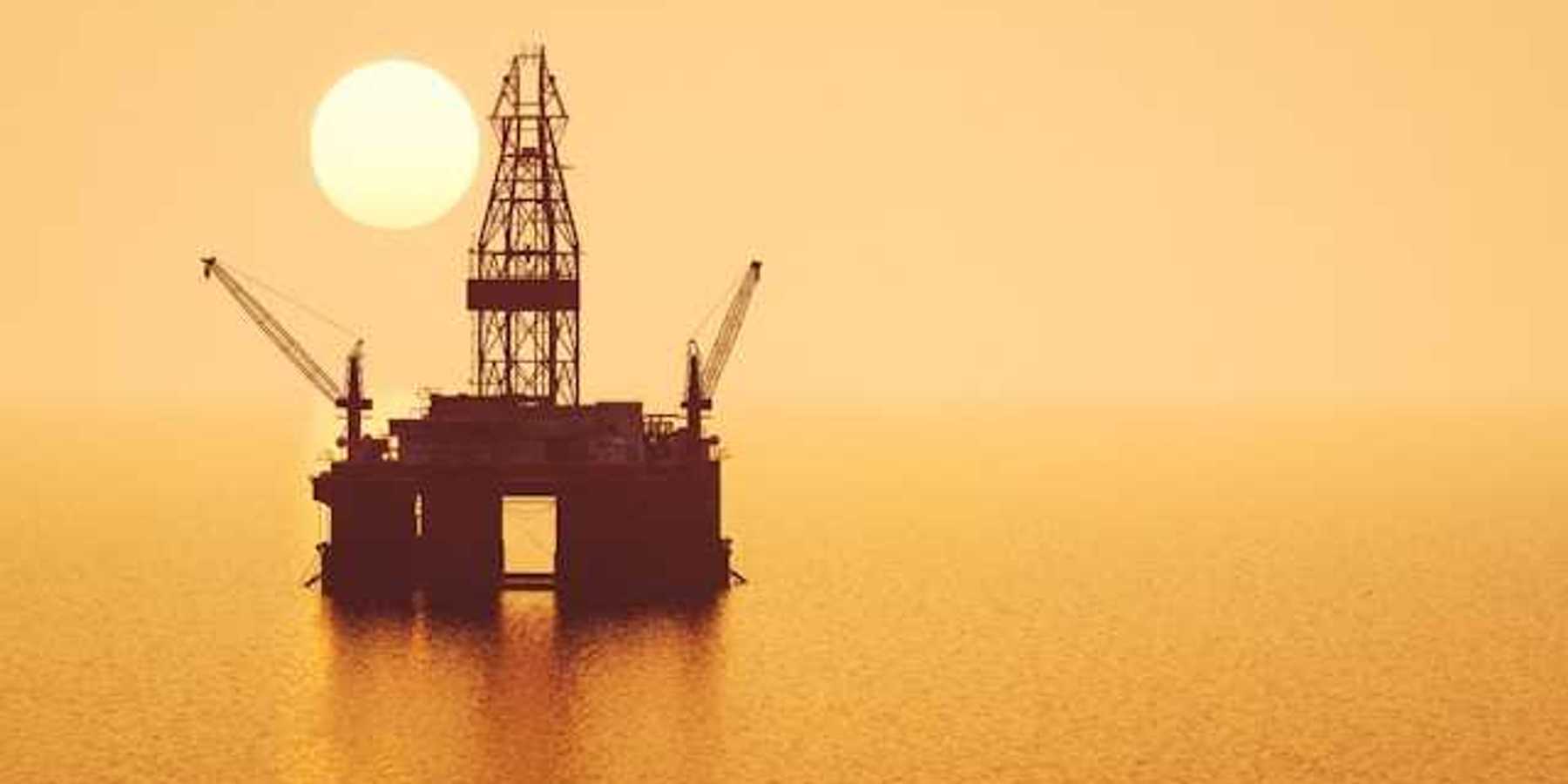 An offshore oil rig with the rising sun behind it